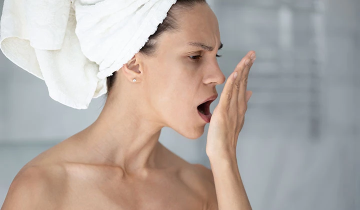 Frau prüft Atem auf Mundgeruch Mundgeruch ist häufig ein Symptom schlechter Mundhygiene