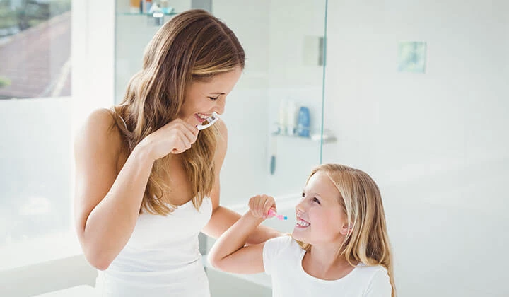 Mutter und Tochter beim Zähne Putzen Mundhygiene für gesunde Mundschleimhaut